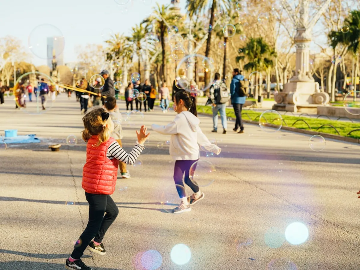 Chicos corriendo detrás de burbujas de jabón en un parque soleado